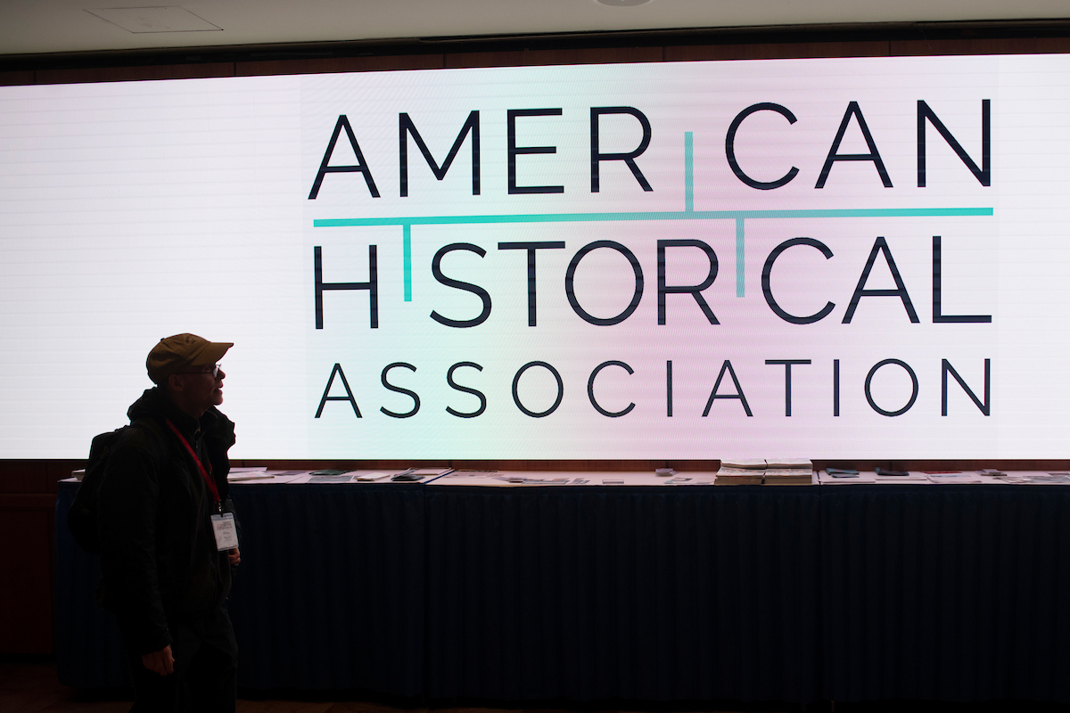 Conference attendee silhouetted against a screen with the American Historical Association logo
